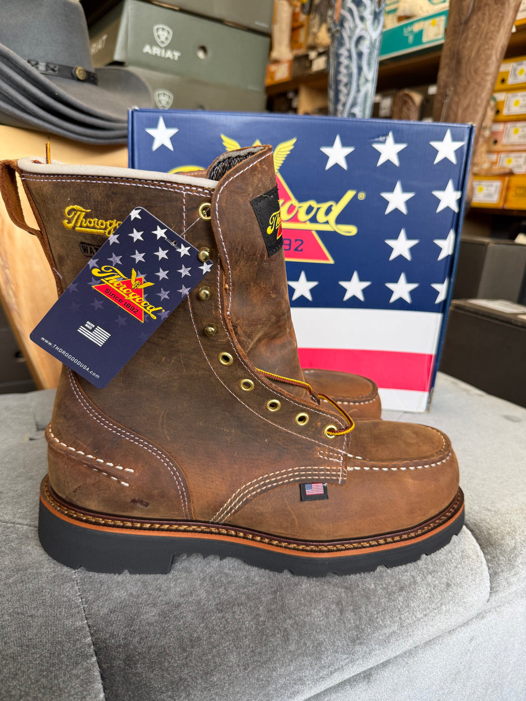 Brown work boot with a tag in front of an American flag-themed box.