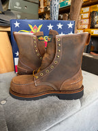 Brown leather boots with gold buttons on a gray surface, with a colorful box in the background.