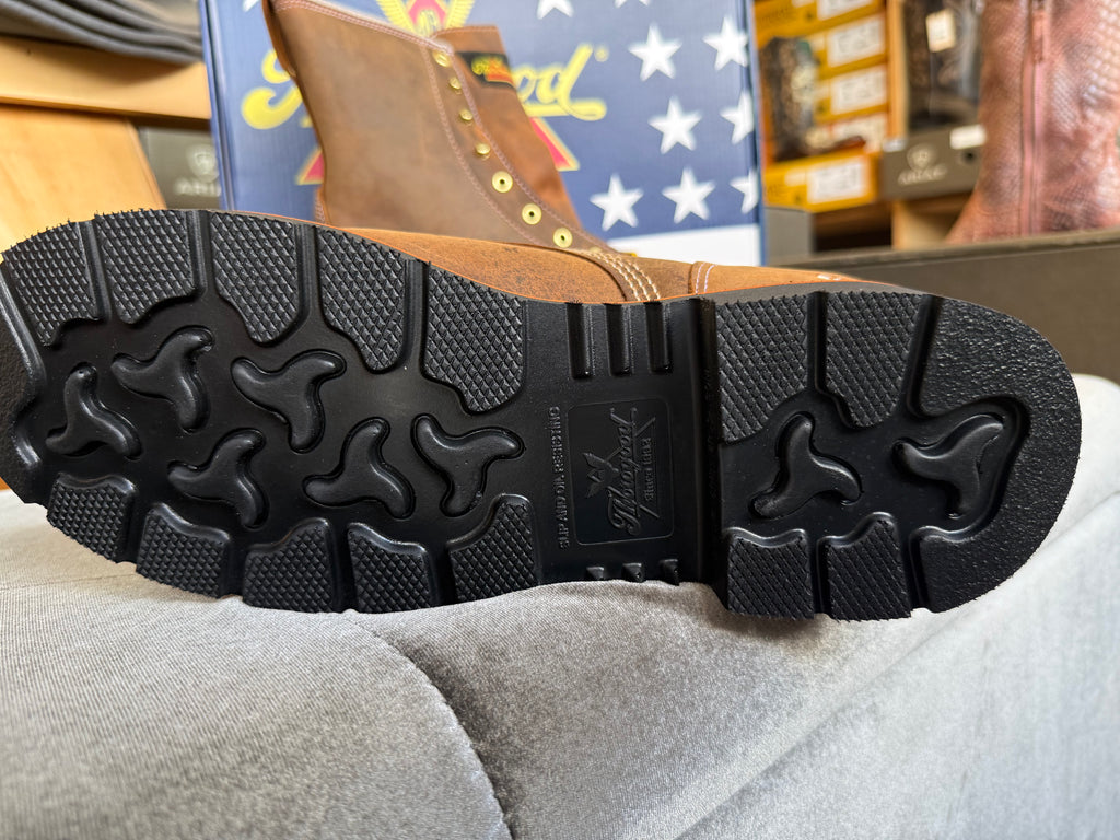 Close-up of a black boot sole with brand logo, placed on a gray surface.