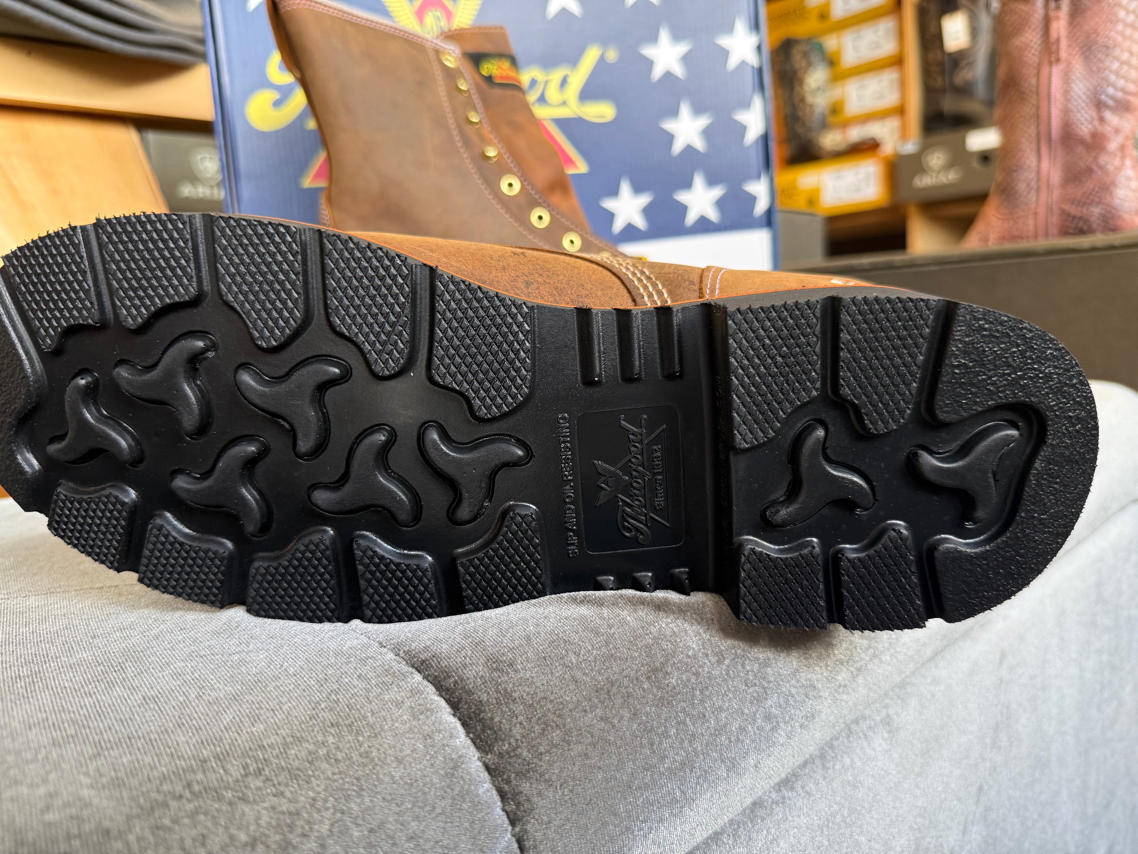 Close-up of a black boot sole with brand logo, placed on a gray surface.