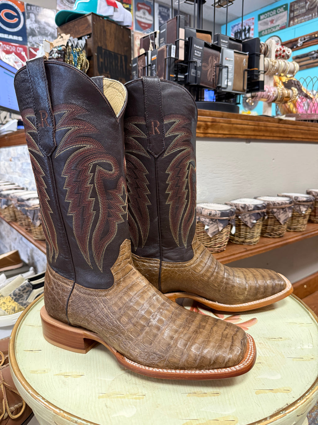 Pair of cowboy boots on a table with a store interior in the background