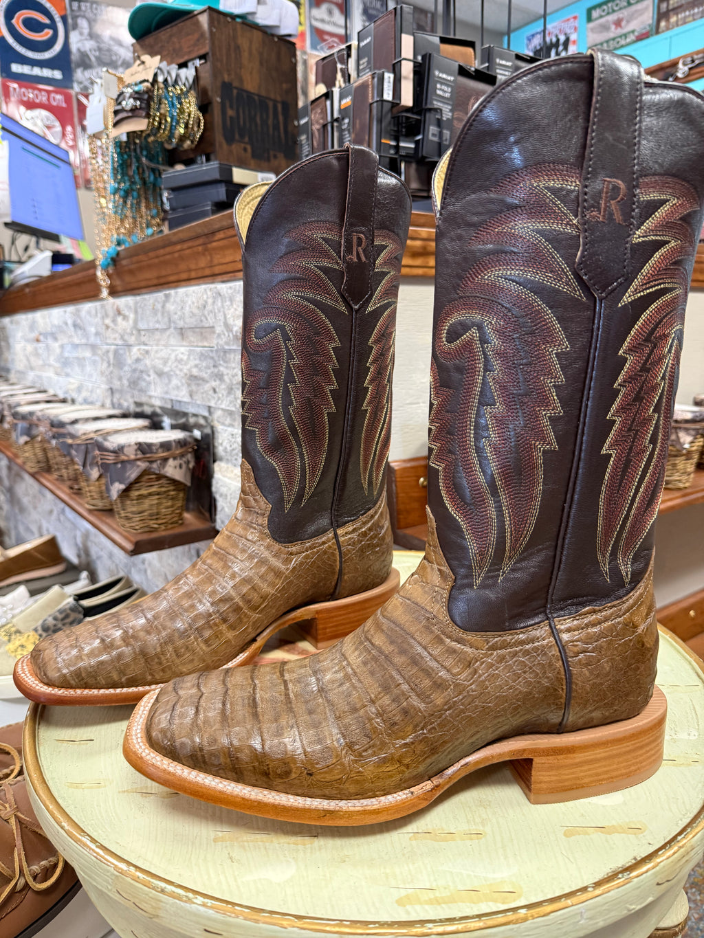 Pair of brown and black cowboy boots with decorative patterns on a round surface.