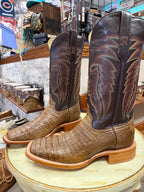 Pair of brown and black cowboy boots with decorative patterns on a round surface.