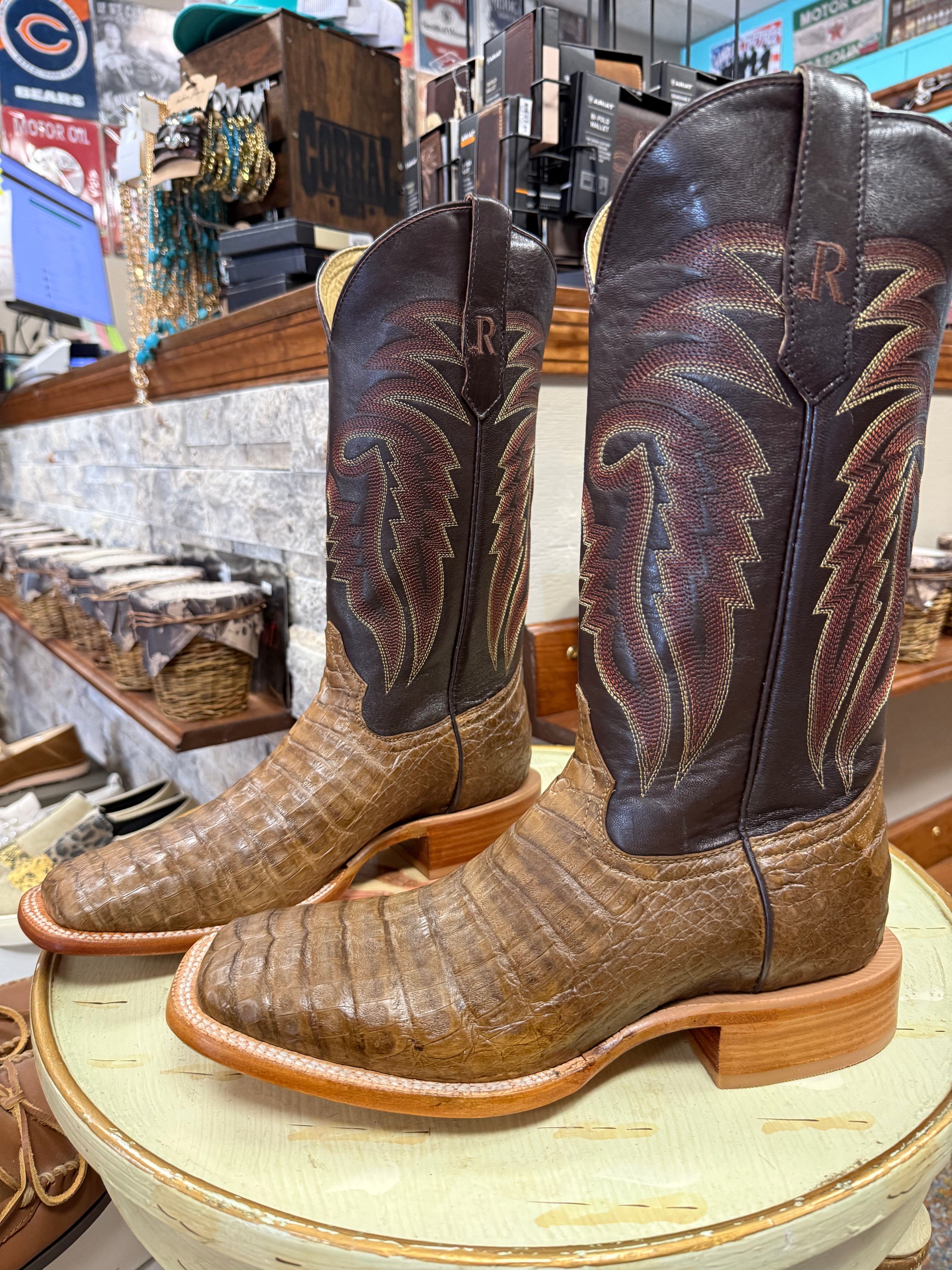 Pair of brown and black cowboy boots with decorative patterns on a round surface.