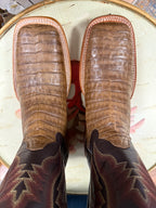 Close-up of brown leather cowboy boots with intricate patterns on a patterned rug.