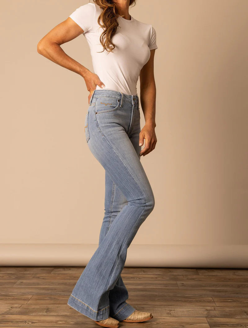 Person wearing a white t-shirt and blue flared jeans on a plain background