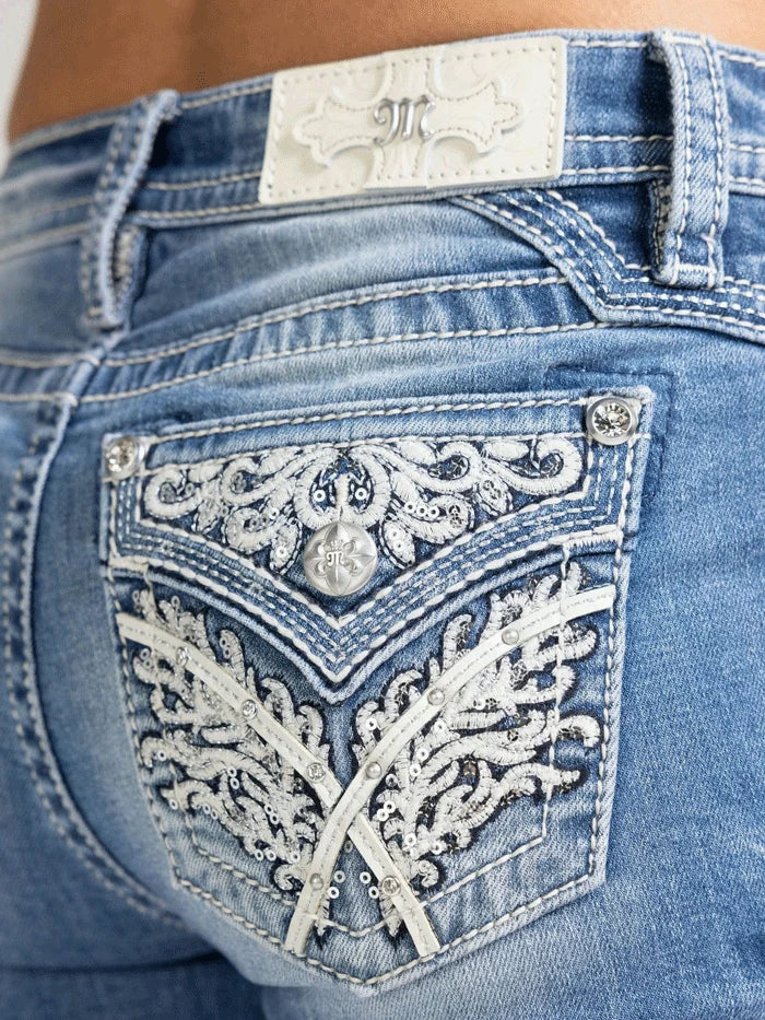 Close-up of blue jeans with decorative front pocket and brand logo.