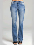 A person wearing light blue denim jeans with a straight-to-medium leg fit, shown from the waist down against a light gray studio background.