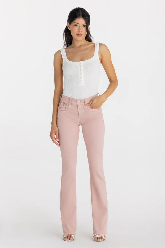 Woman wearing a white sleeveless top and pink jeans on a white background