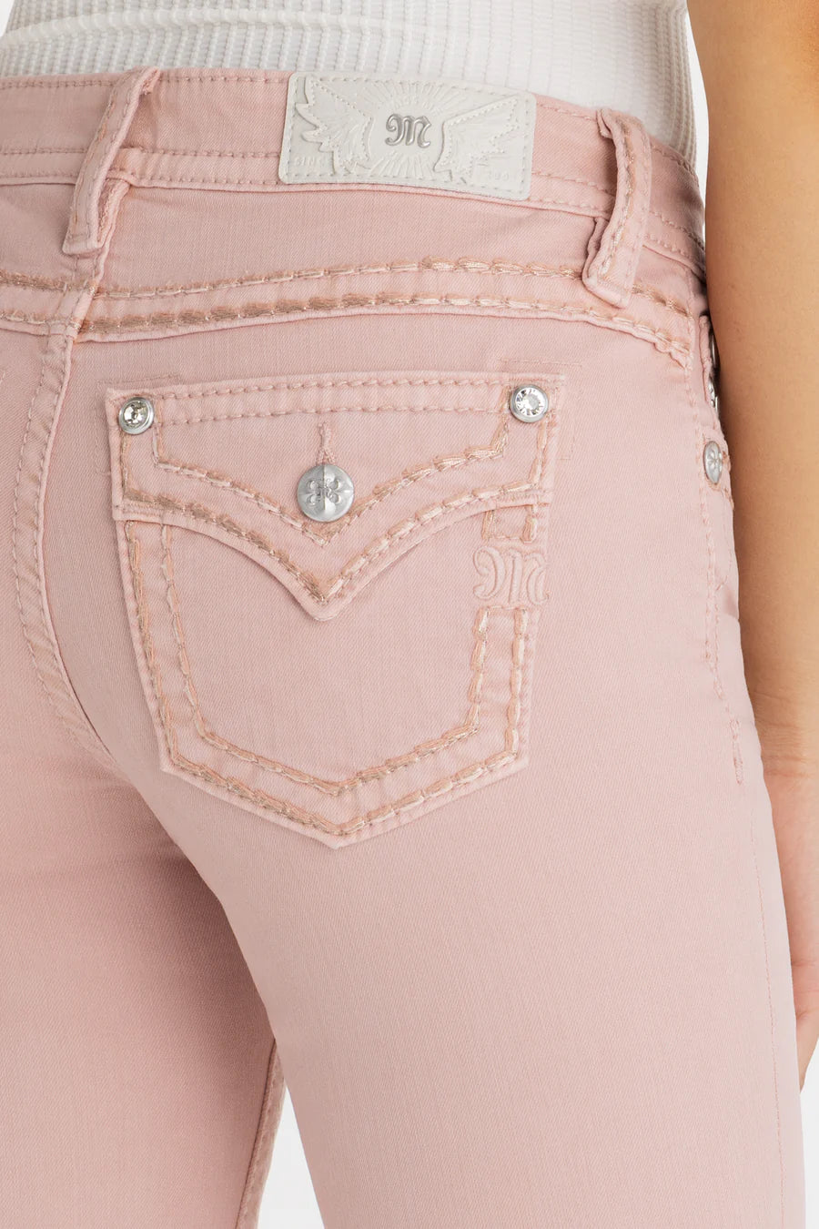Close-up of pink jeans with a brand label on a white background
