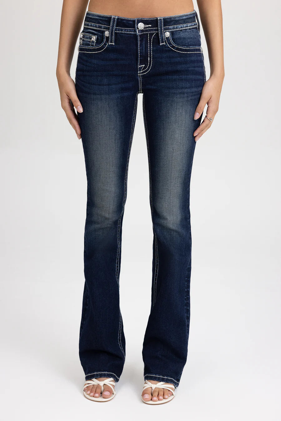 Dark blue jeans worn by a person on a white background