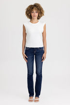 Woman wearing a white sleeveless top and blue jeans on a white background