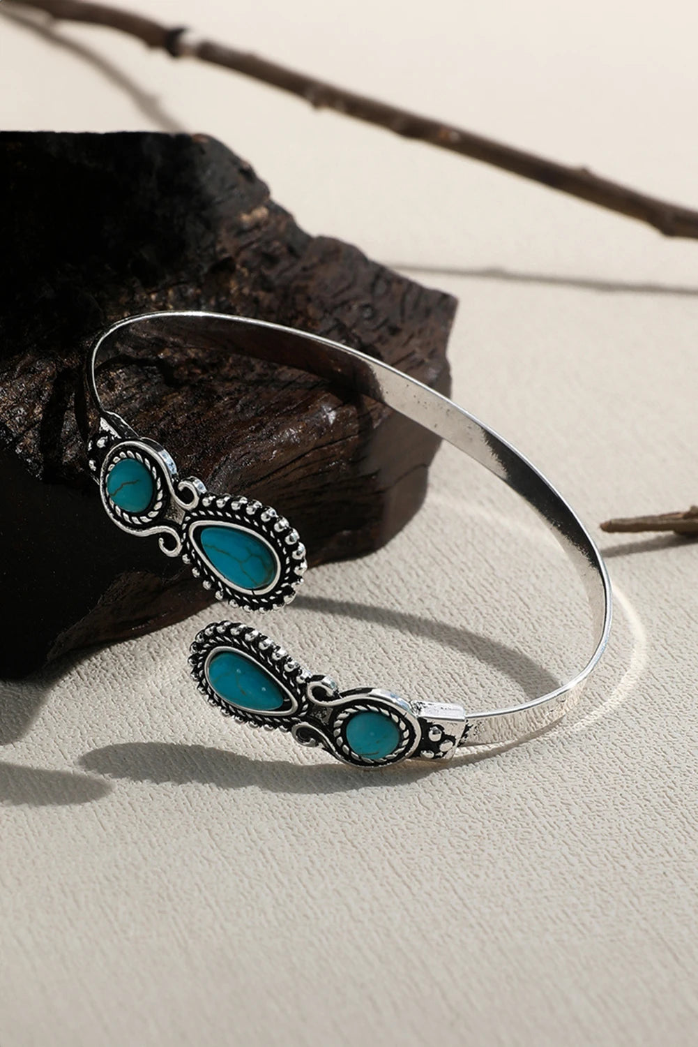 Silver bracelet with turquoise stones on a stone surface