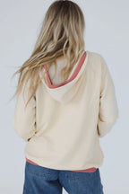 Person wearing a beige hoodie with a pink interior on a plain background