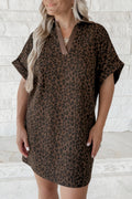 Woman wearing a leopard print dress against a white brick wall.
