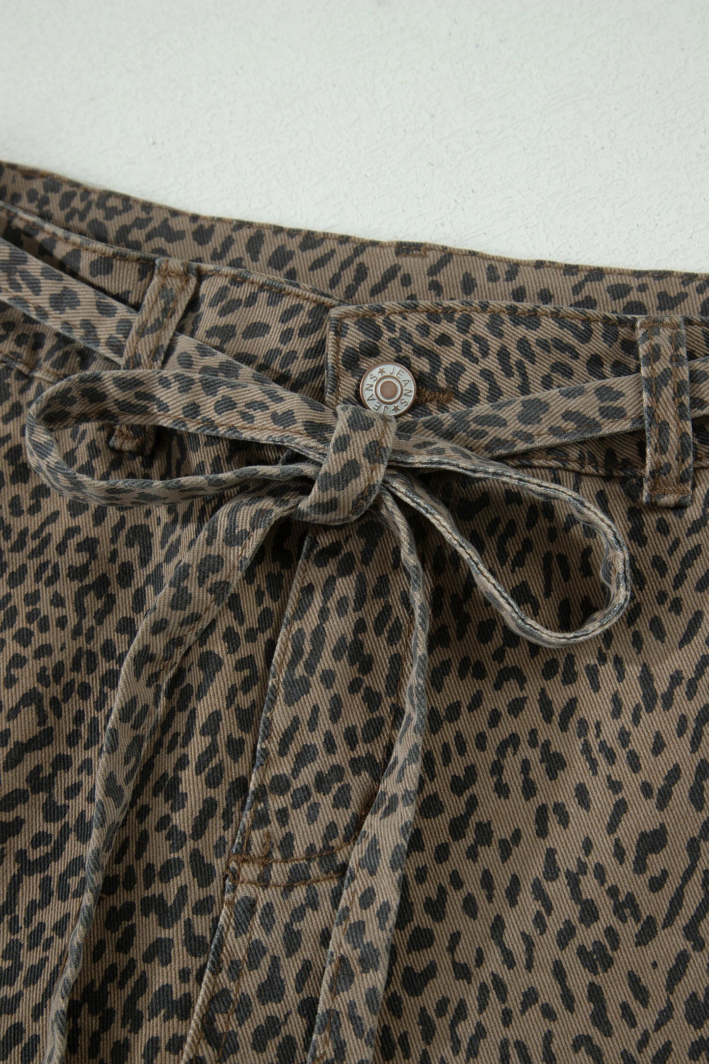 Leopard print pants with a tie waist on a white background