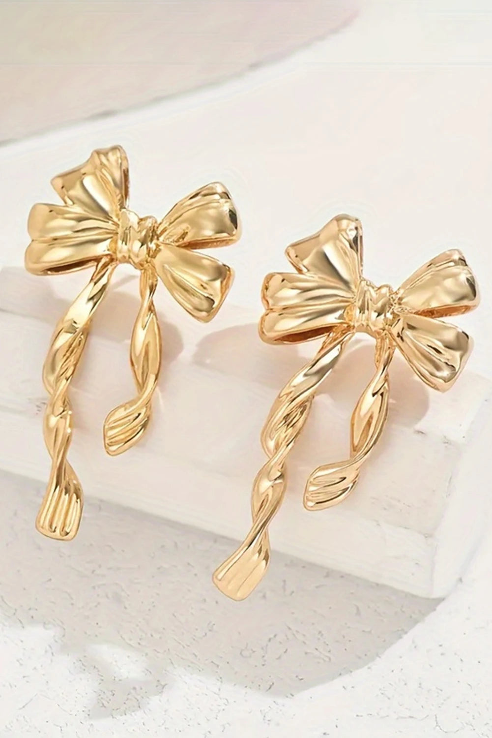 Gold bow-shaped earrings on a light background