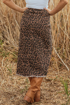 Person wearing a leopard print skirt and brown boots in a field of dry grass.