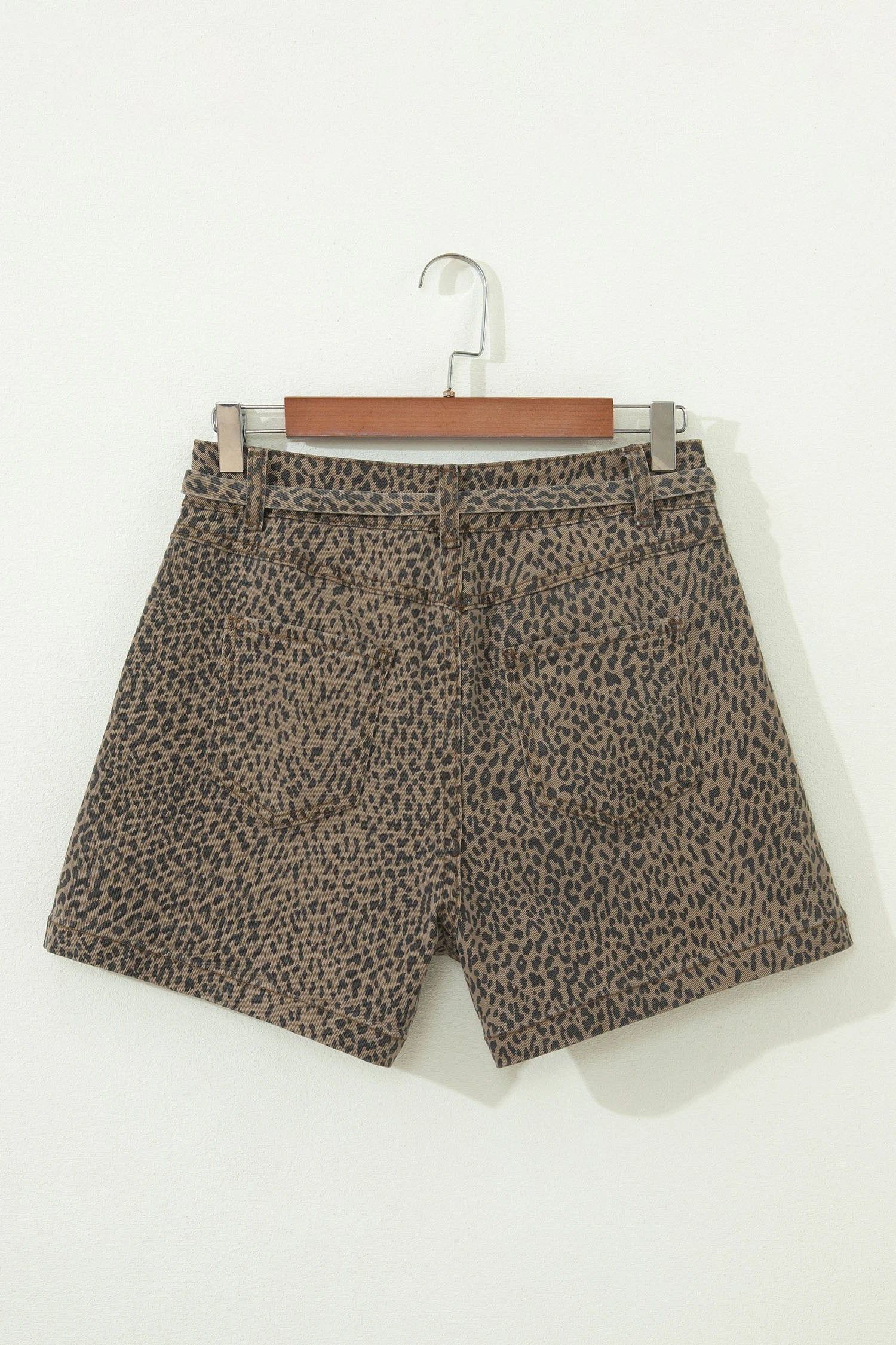 Leopard print shorts on a hanger against a white background