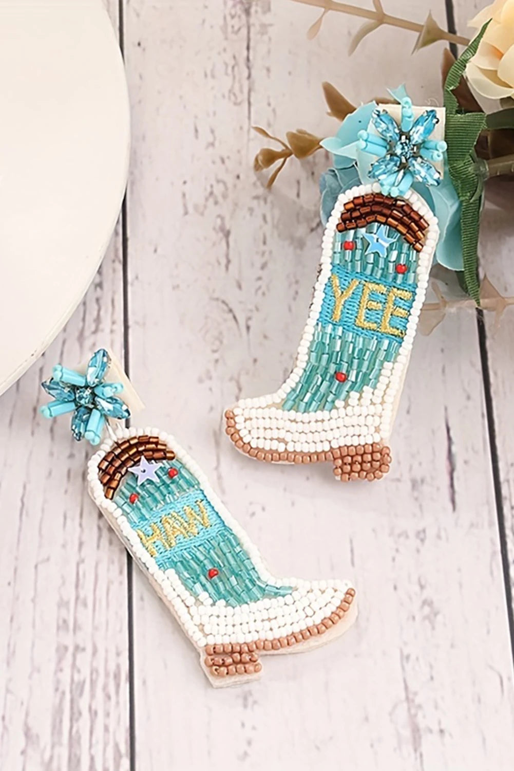 Decorative beaded boot ornaments with 'Yee Haw' text on a wooden surface.