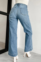 Blue jeans worn by a person on a plain background