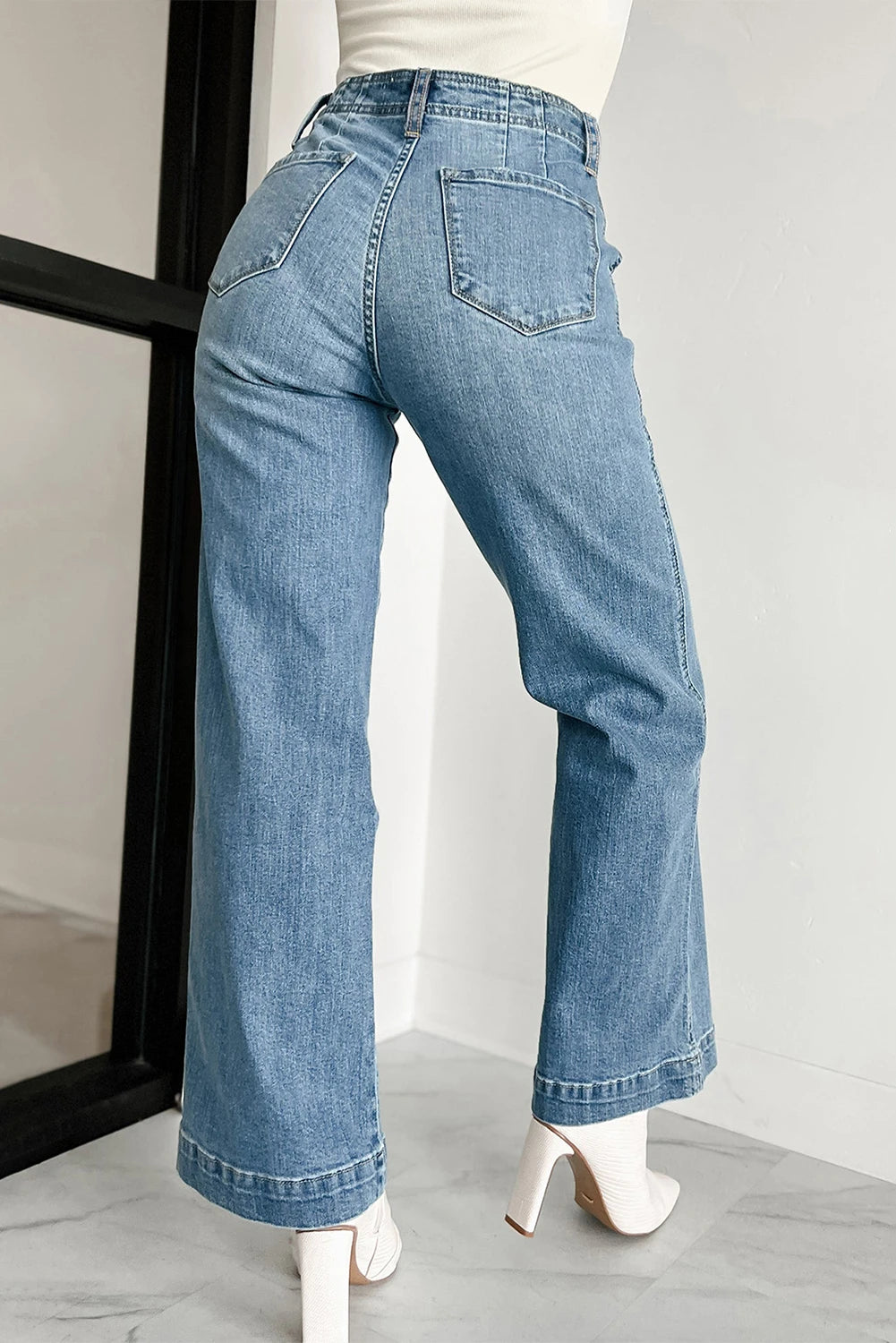 Blue jeans worn by a person on a plain background