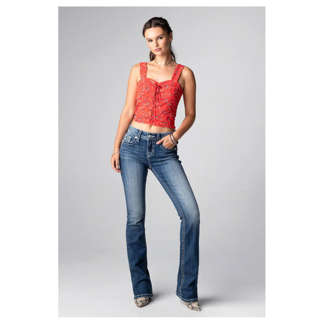 Woman wearing a red top and blue jeans on a gray background