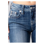 Close-up of blue jeans with decorative buttons on a white background