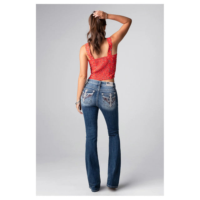 Woman wearing a red top and blue jeans on a gray background